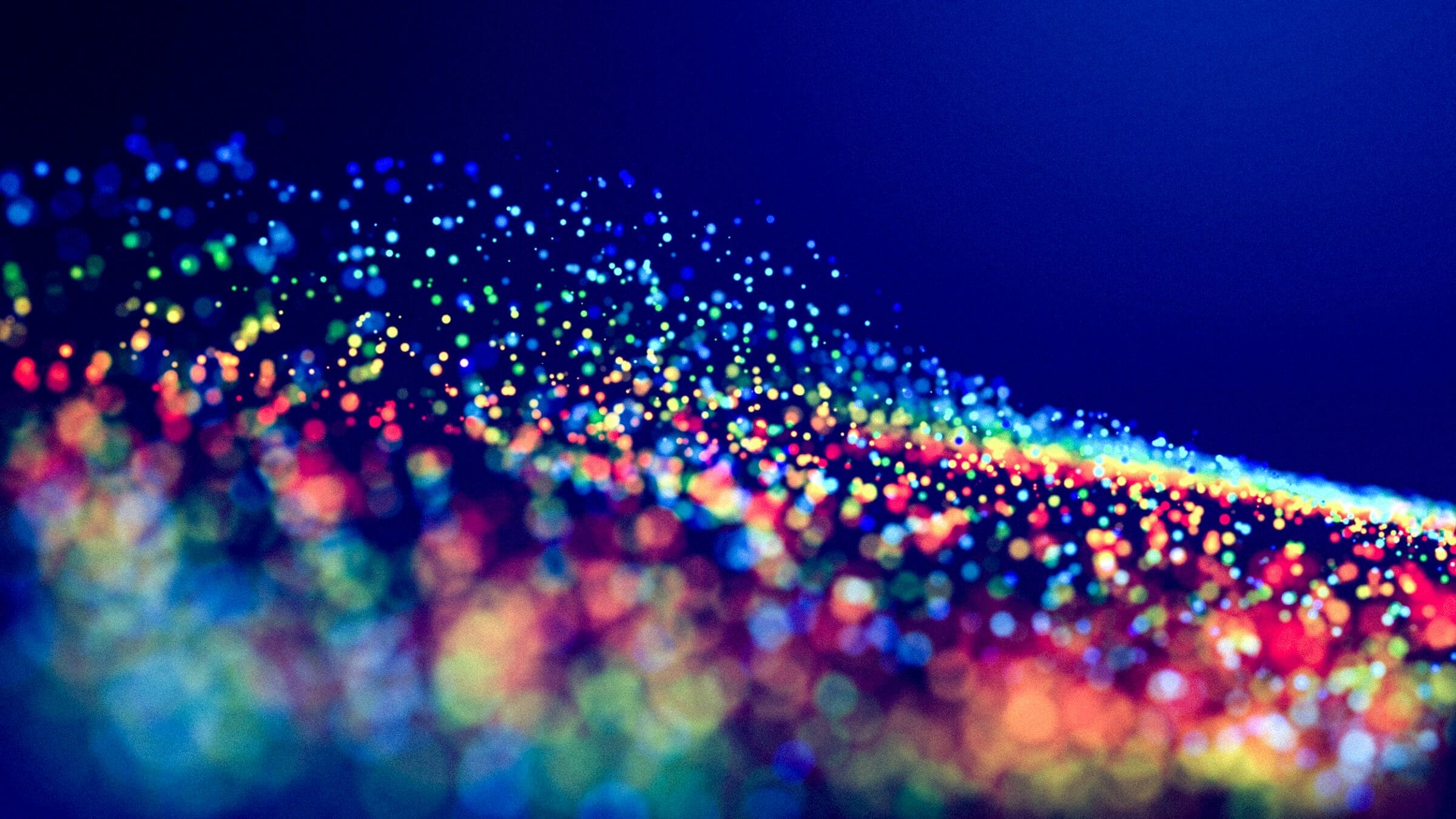 cloud of multicolored particles fly in air slowly or float in liquid like sparkles on dark blue background. Beautiful bokeh light effects with glowing particles