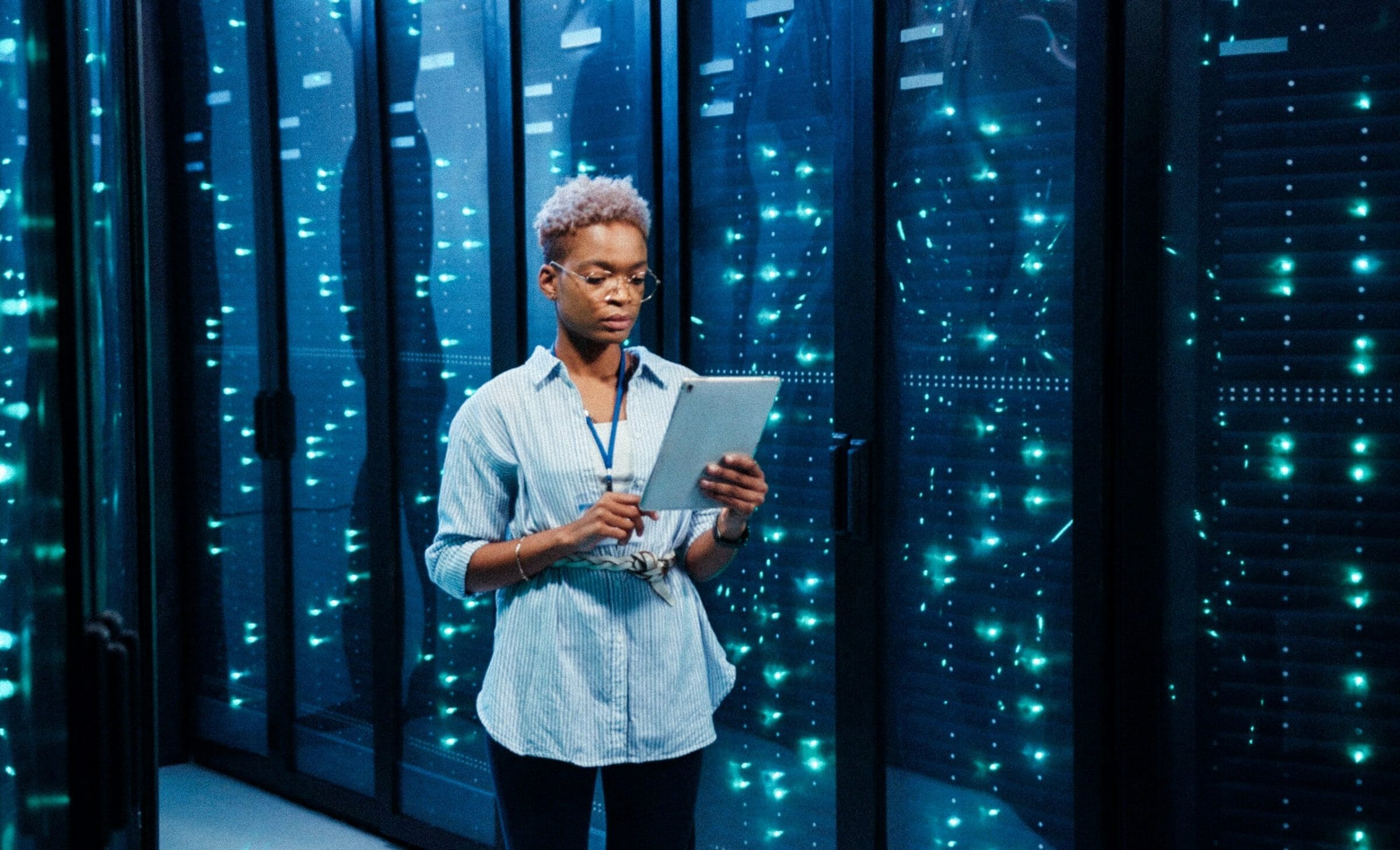 Female excalibur IT administrator walking in server corridor diagnosing hardware system performance in data center cyber secure storage.